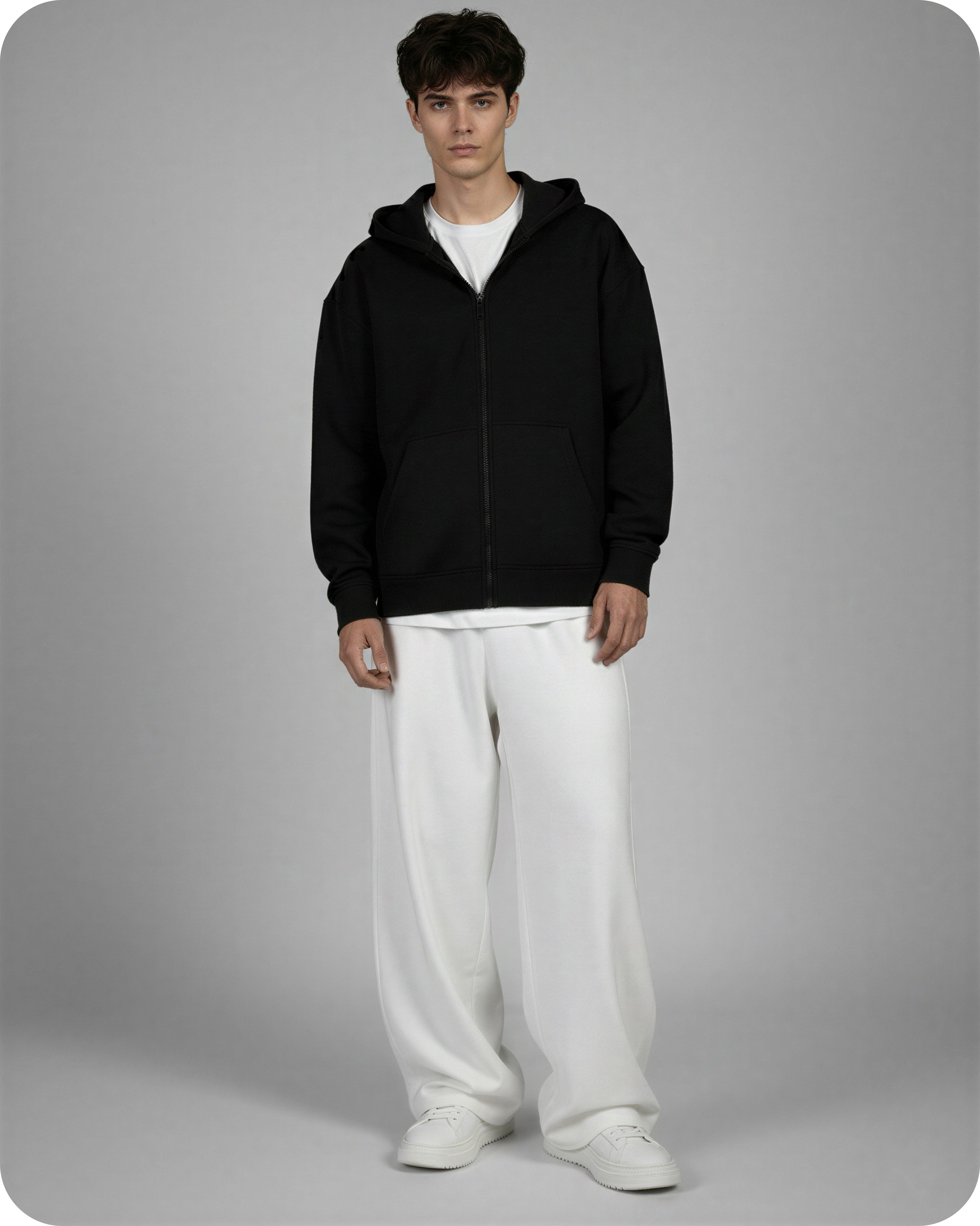 Person wearing a black hoodie and white pants on a gray background