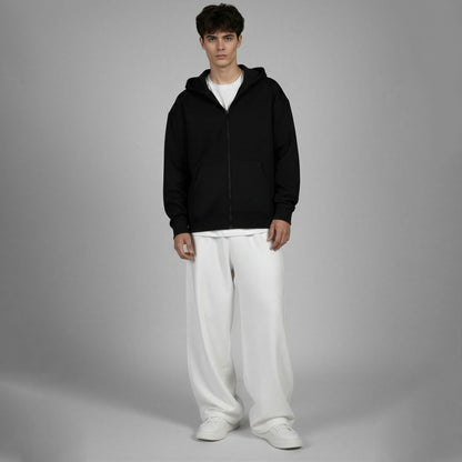 Person wearing a black hoodie and white pants on a gray background