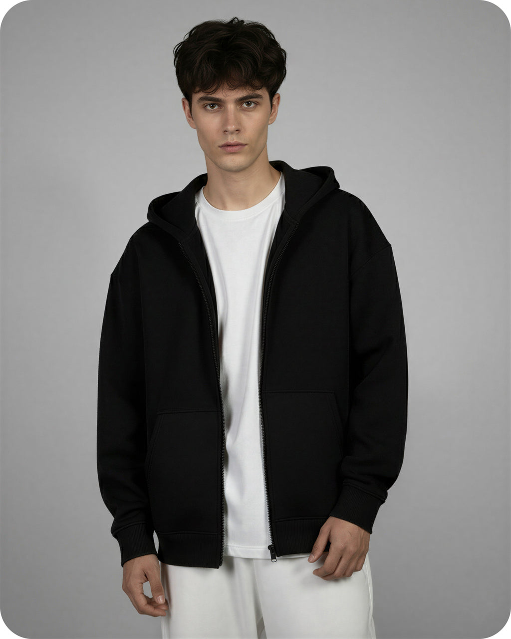 Person wearing a black hoodie over a white shirt on a gray background