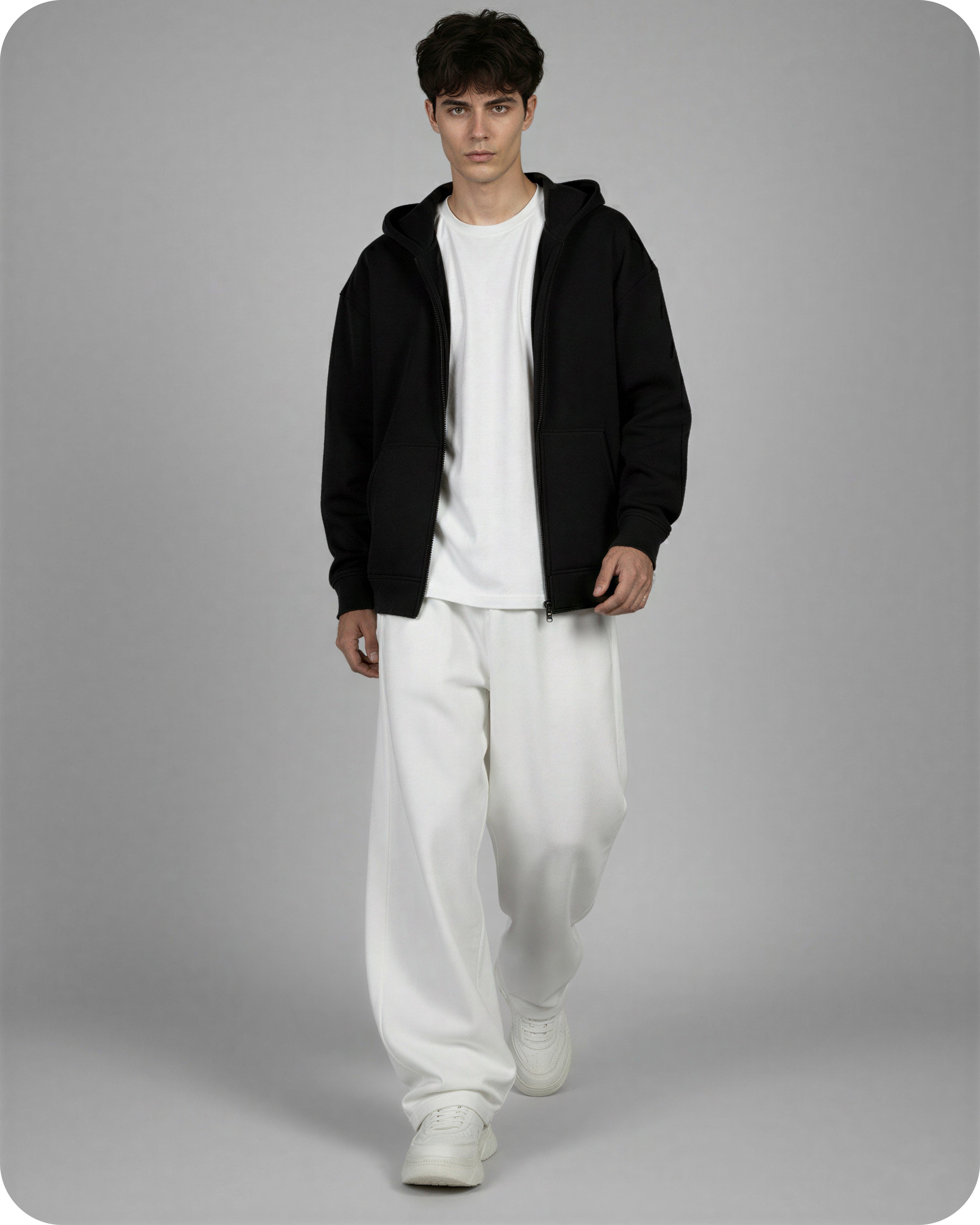 Person wearing a black hoodie, white t-shirt, and white pants on a gray background