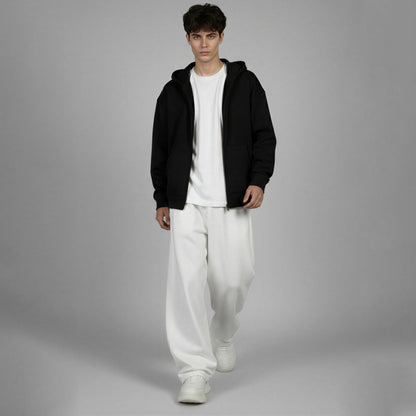 Person wearing a black hoodie, white t-shirt, and white pants on a gray background