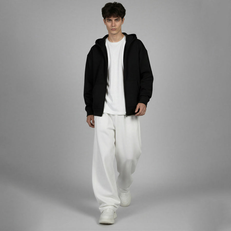 Person wearing a black hoodie, white t-shirt, and white pants on a gray background
