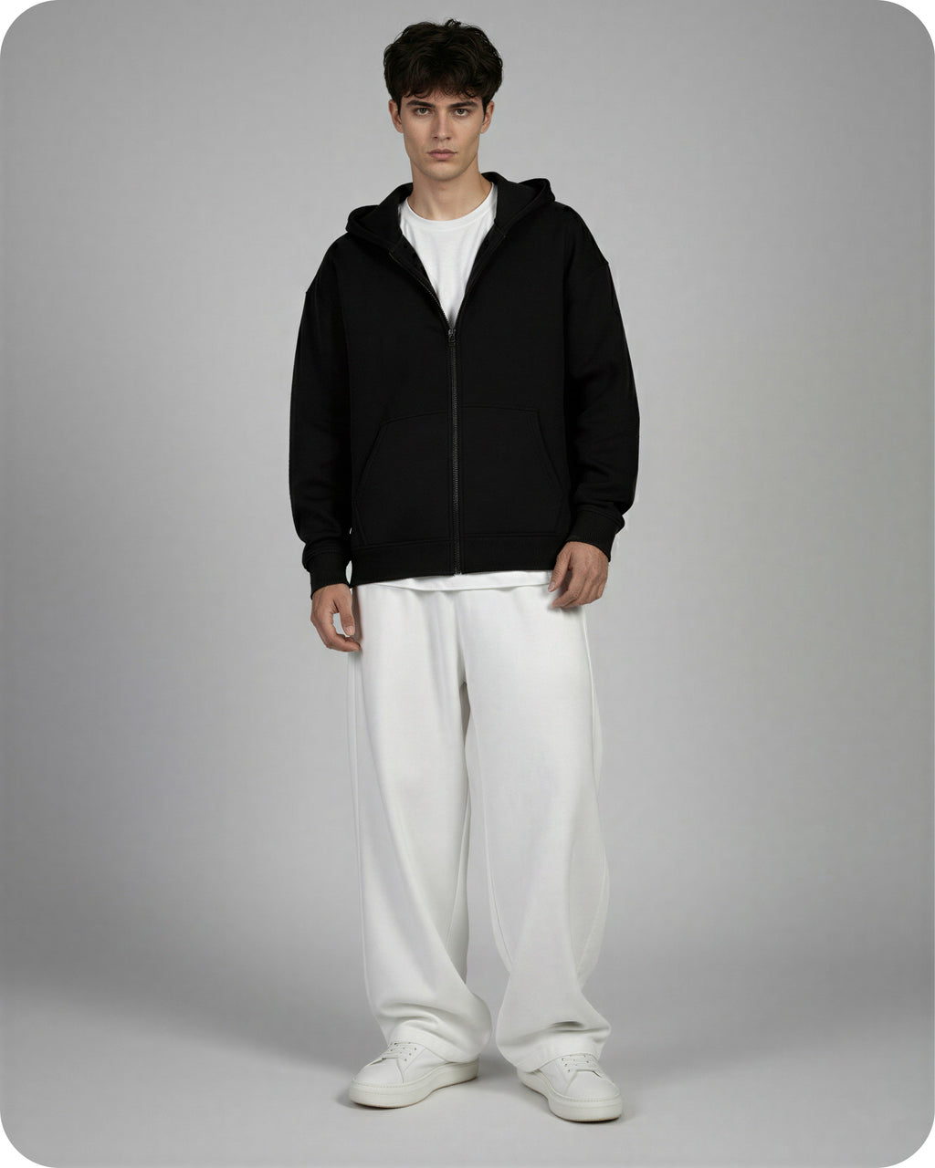 Man wearing a black hoodie and white pants on a gray background