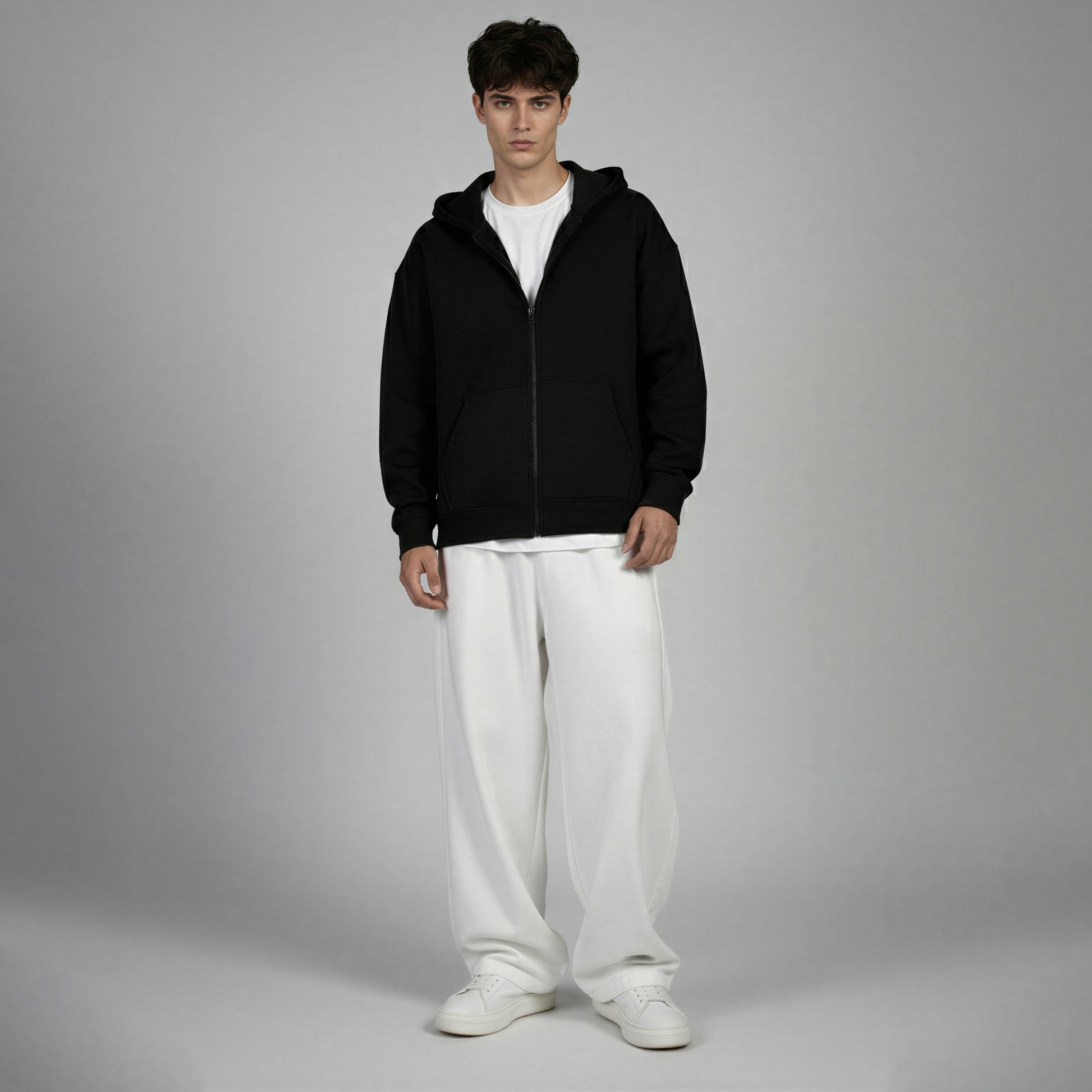 Man wearing a black hoodie and white pants on a gray background