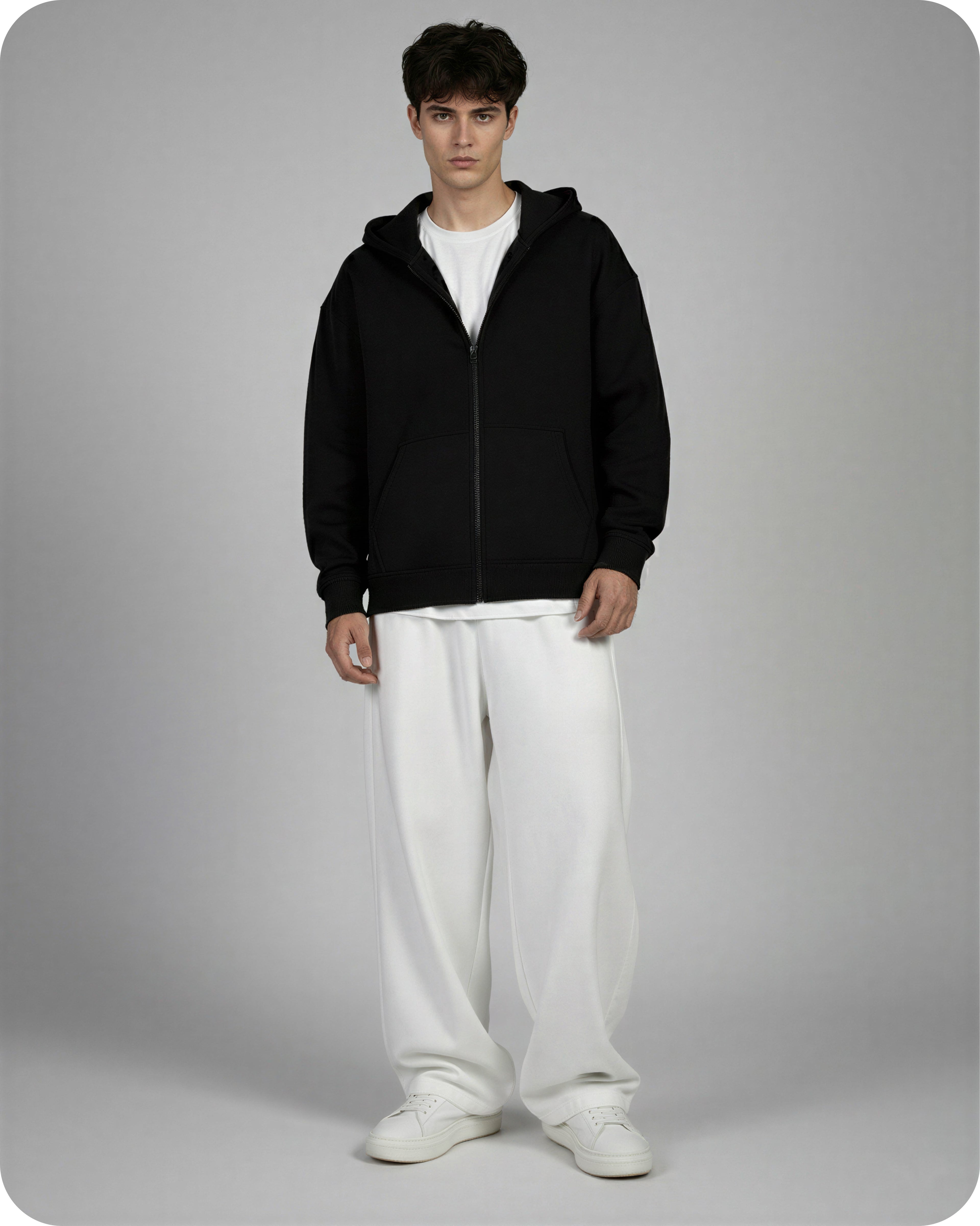 Man wearing a black hoodie and white pants on a gray background