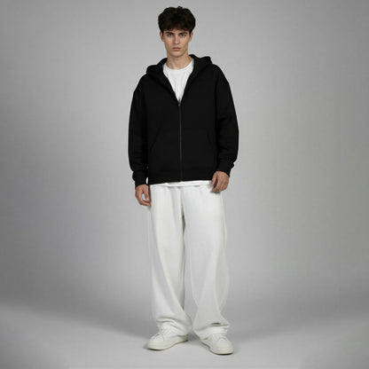 Man wearing a black hoodie and white pants on a gray background