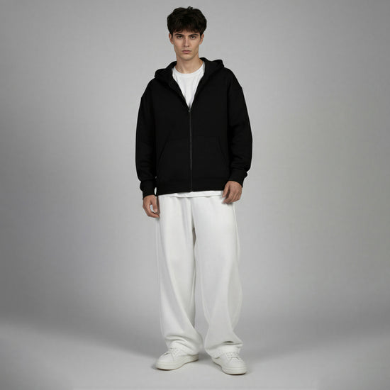 Man wearing a black hoodie and white pants on a gray background