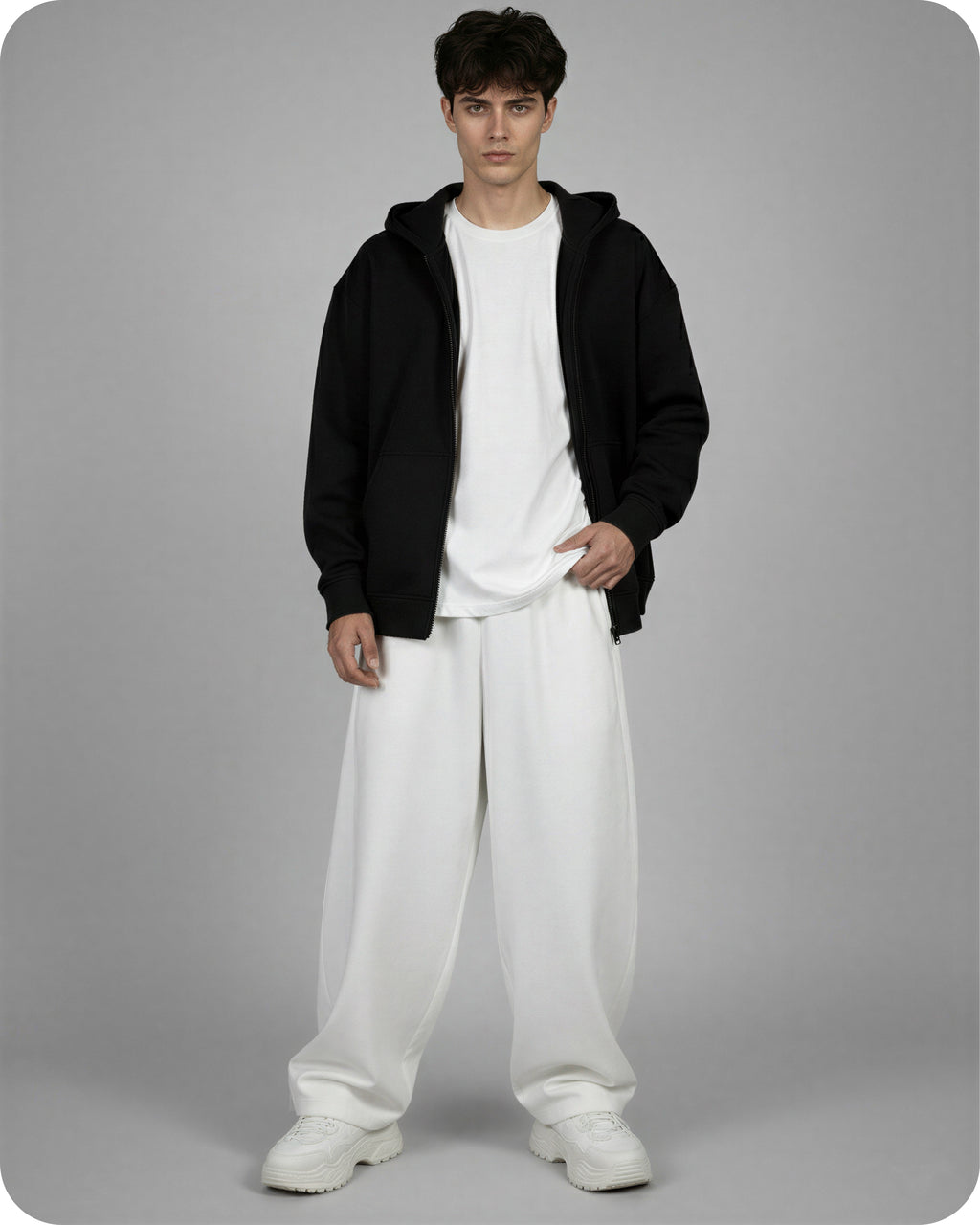 Person wearing a black hoodie, white t-shirt, and white pants on a gray background