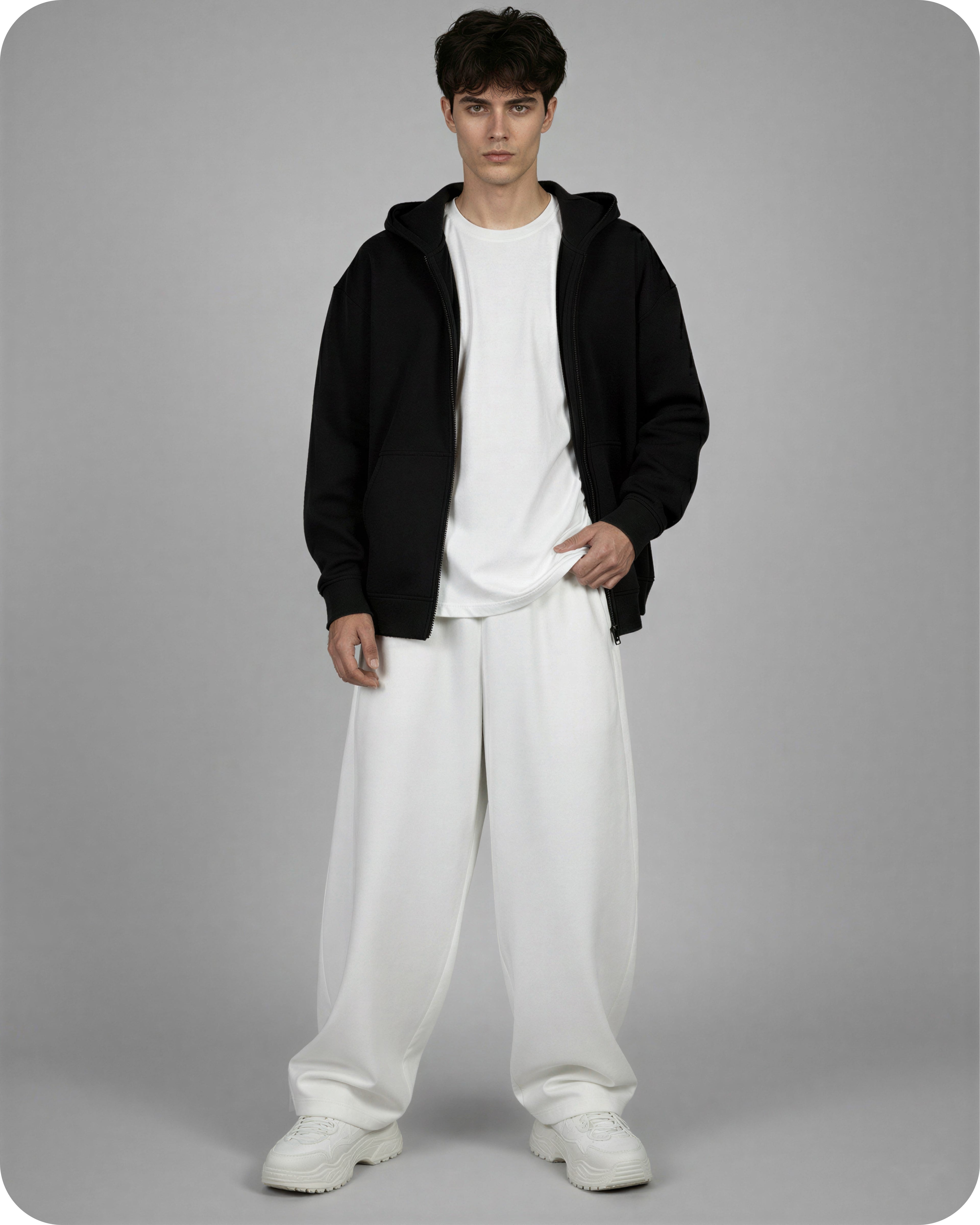 Person wearing a black hoodie, white t-shirt, and white pants on a gray background
