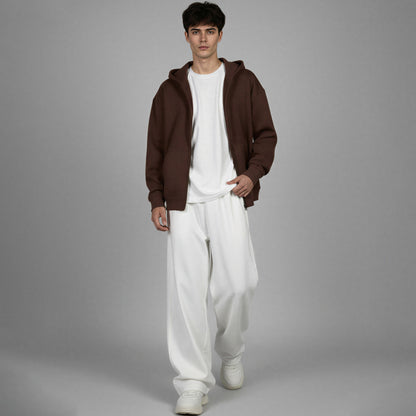 Man wearing a brown hoodie and white pants on a gray background