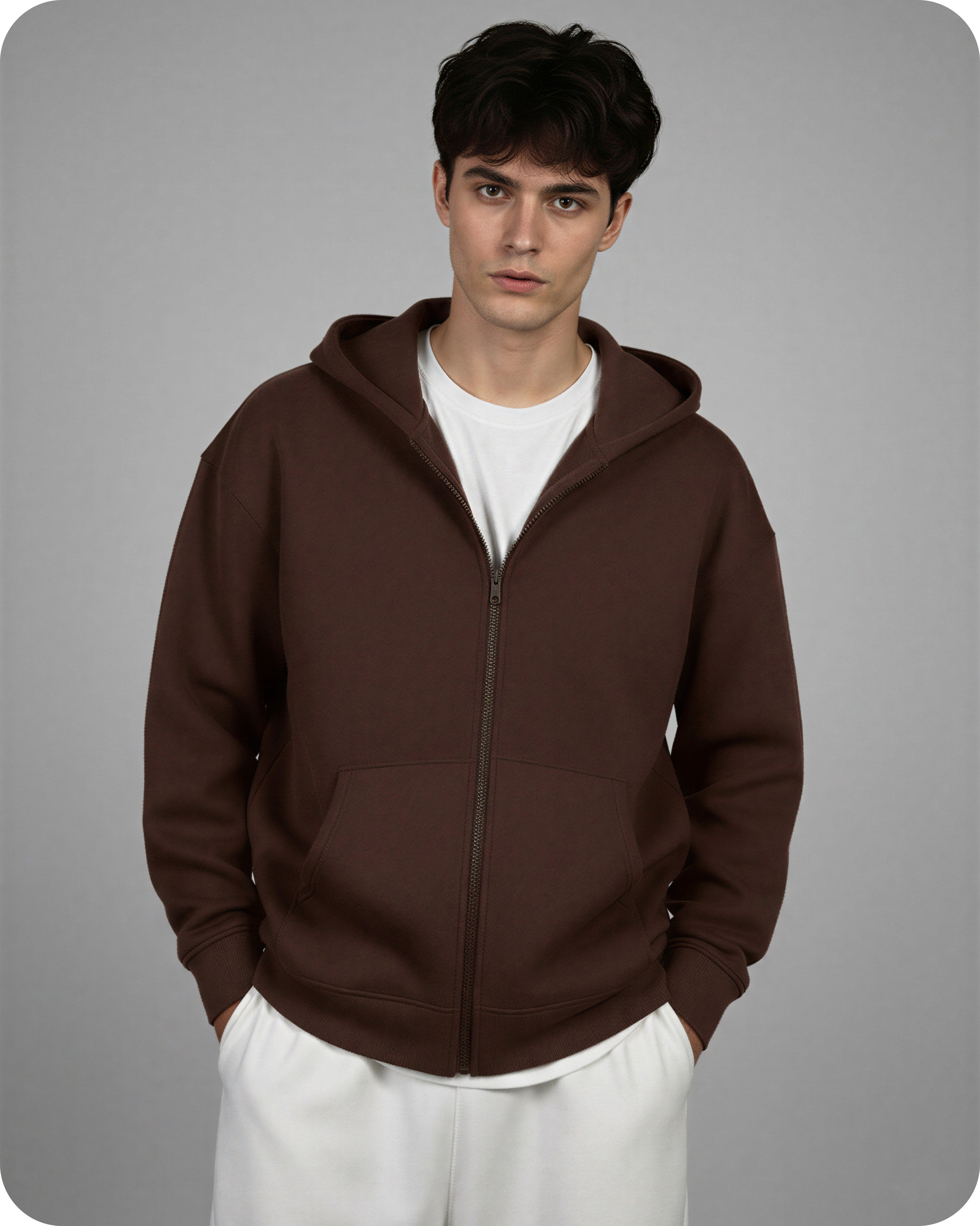 Man wearing a brown hoodie over a white shirt on a gray background