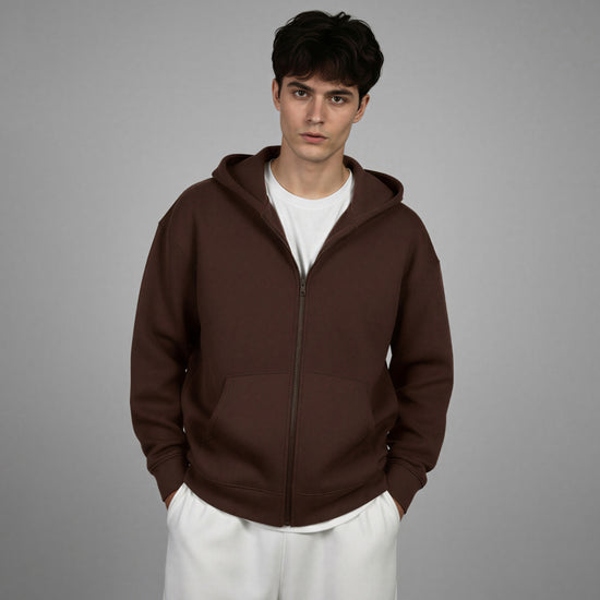 Man wearing a brown hoodie over a white shirt on a gray background