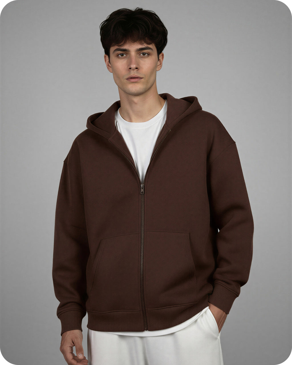 Man wearing a brown hoodie over a white shirt on a gray background