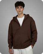 Man wearing a brown hoodie over a white shirt on a gray background