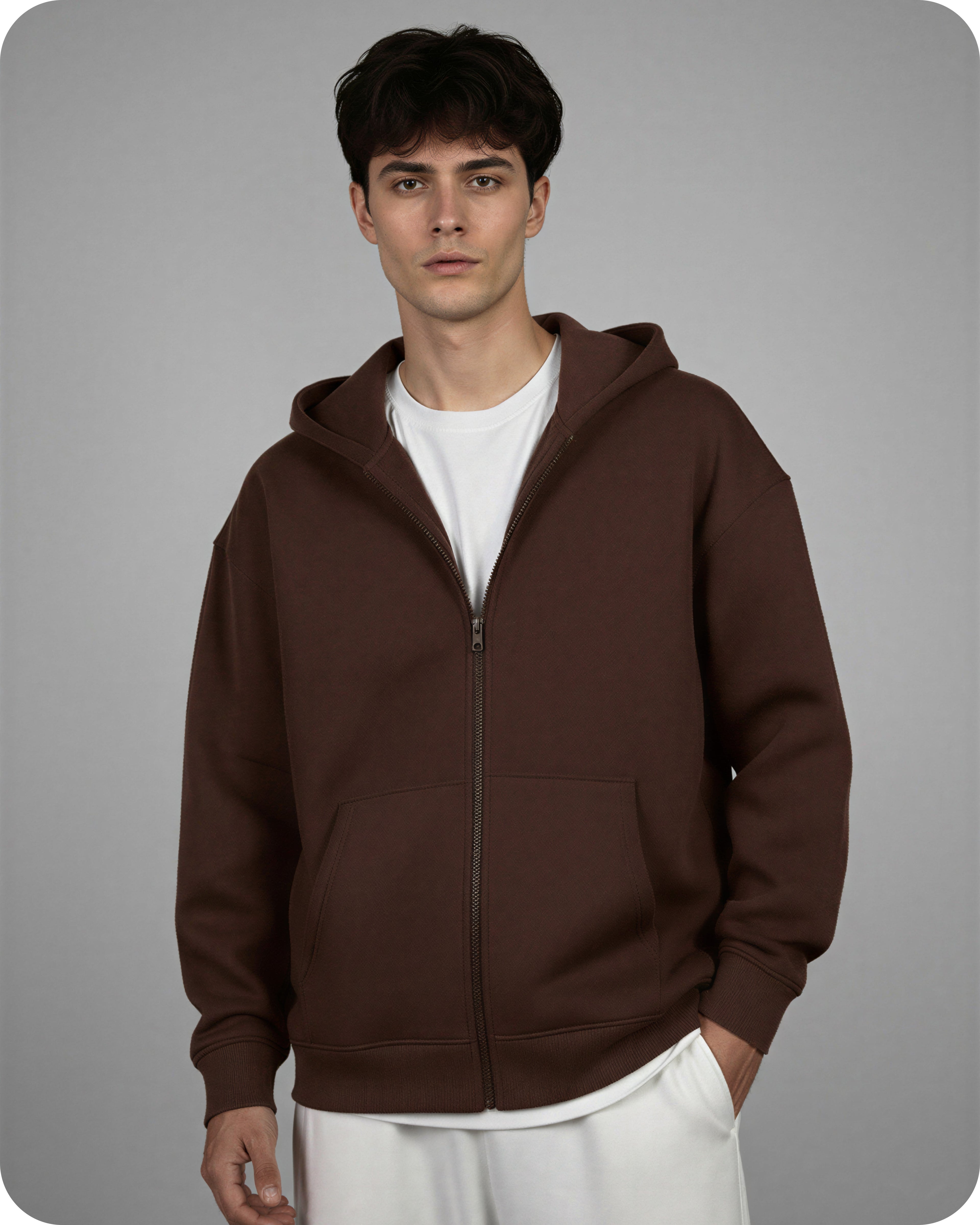 Man wearing a brown hoodie over a white shirt on a gray background