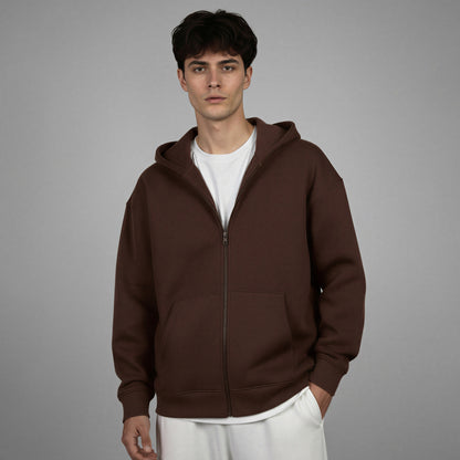 Man wearing a brown hoodie over a white shirt on a gray background