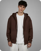 Man wearing a brown hoodie over a white shirt on a gray background