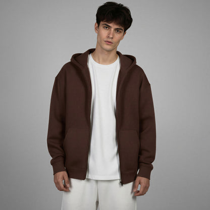 Man wearing a brown hoodie over a white shirt on a gray background