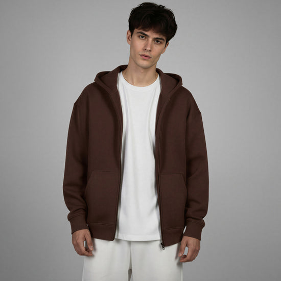 Man wearing a brown hoodie over a white shirt on a gray background