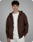 Man wearing a brown hoodie over a white shirt on a gray background