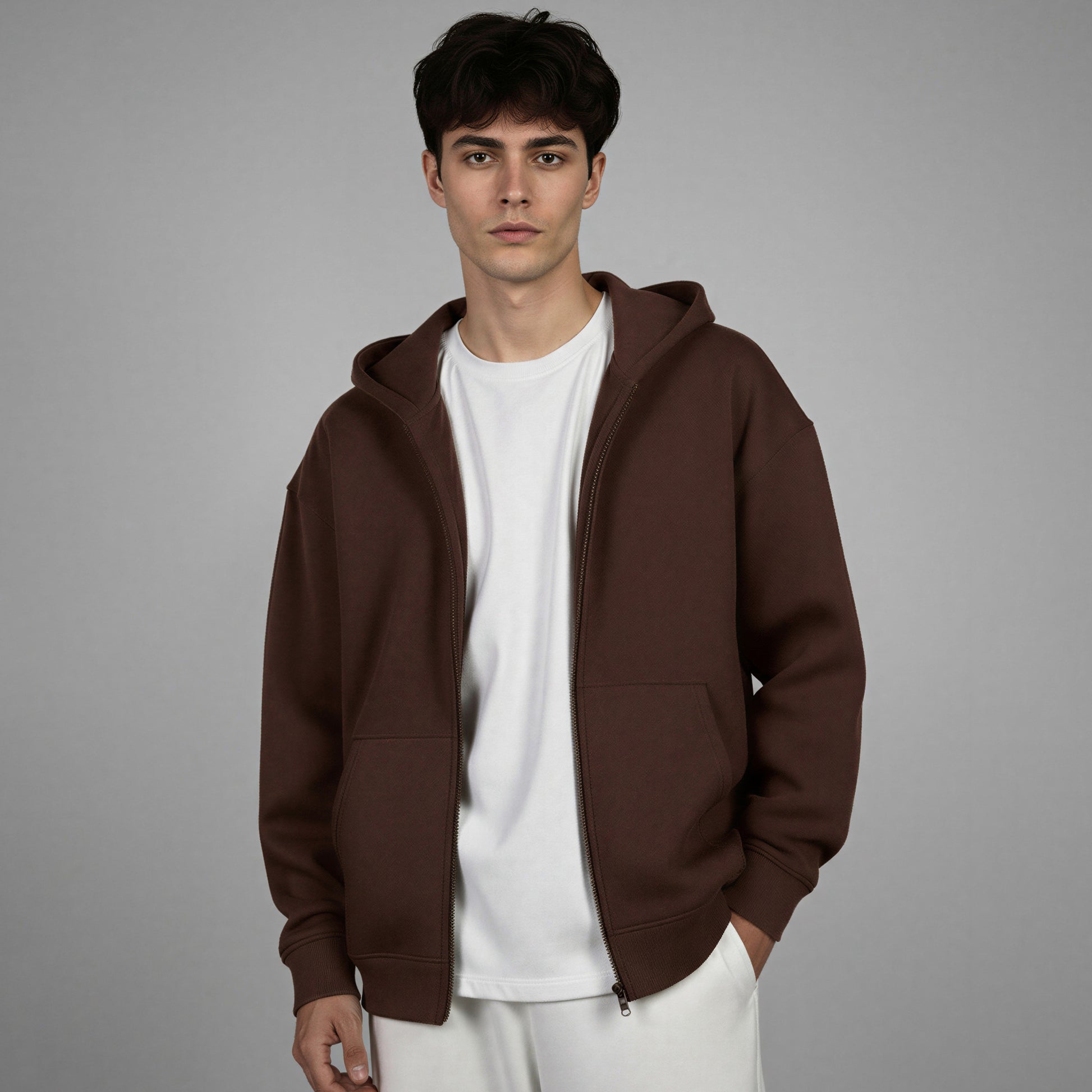 Man wearing a brown hoodie over a white shirt on a gray background