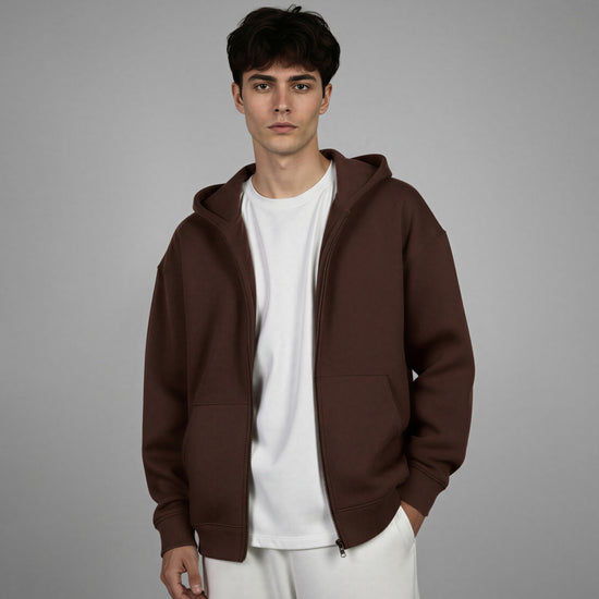 Man wearing a brown hoodie over a white shirt on a gray background