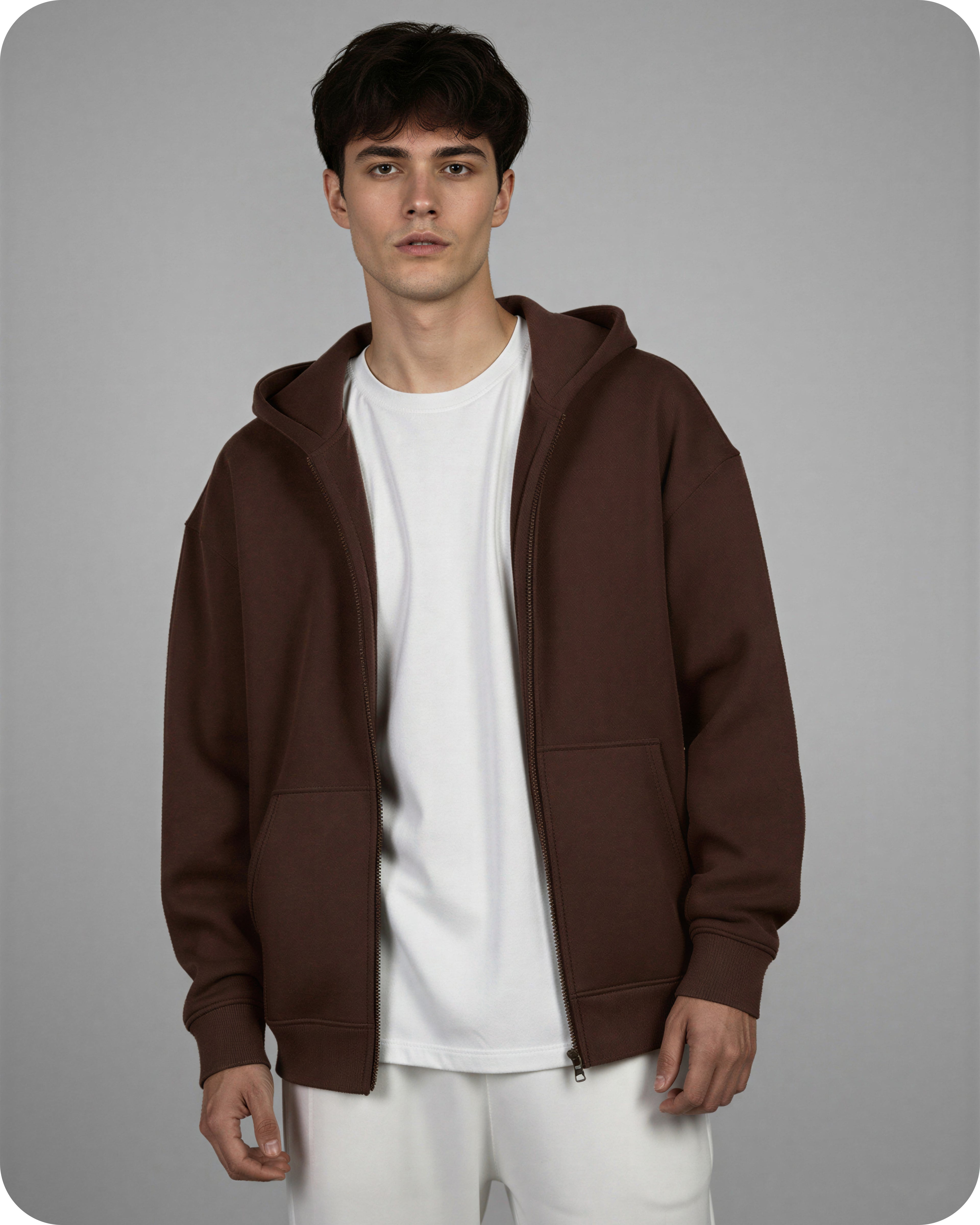 Man wearing a brown hoodie over a white shirt on a gray background