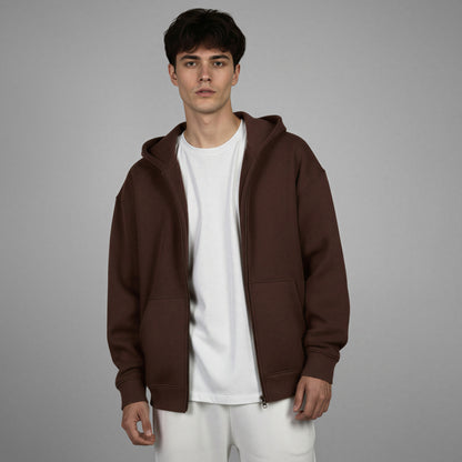 Man wearing a brown hoodie over a white shirt on a gray background