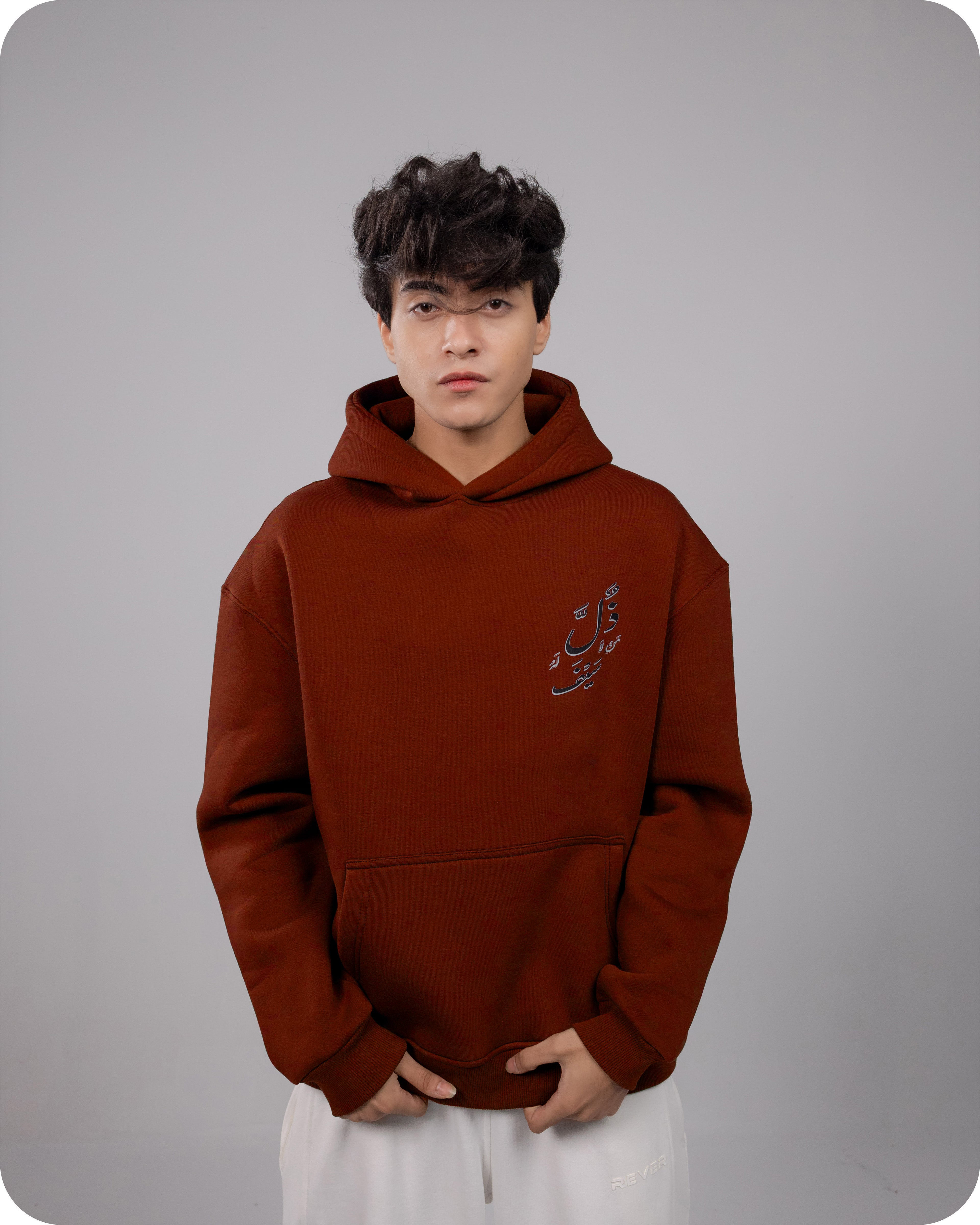 Person wearing a Burgundy hoodie with a logo on a gray background