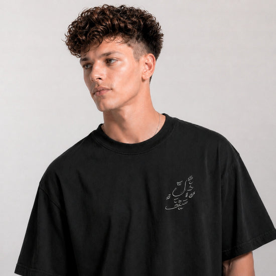Man wearing a black t-shirt with a small design on a plain background