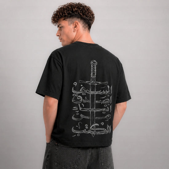 Person wearing a black t-shirt with a white graphic design on the back against a gray background