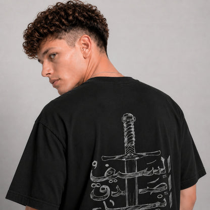 Person wearing a black t-shirt with a graphic design on the back against a gray background