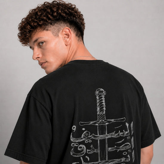 Person wearing a black t-shirt with a graphic design on the back against a gray background