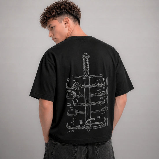 Person wearing a black t-shirt with a white graphic design on the back against a gray background