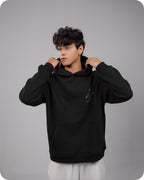 Person wearing a black hoodie against a gray background