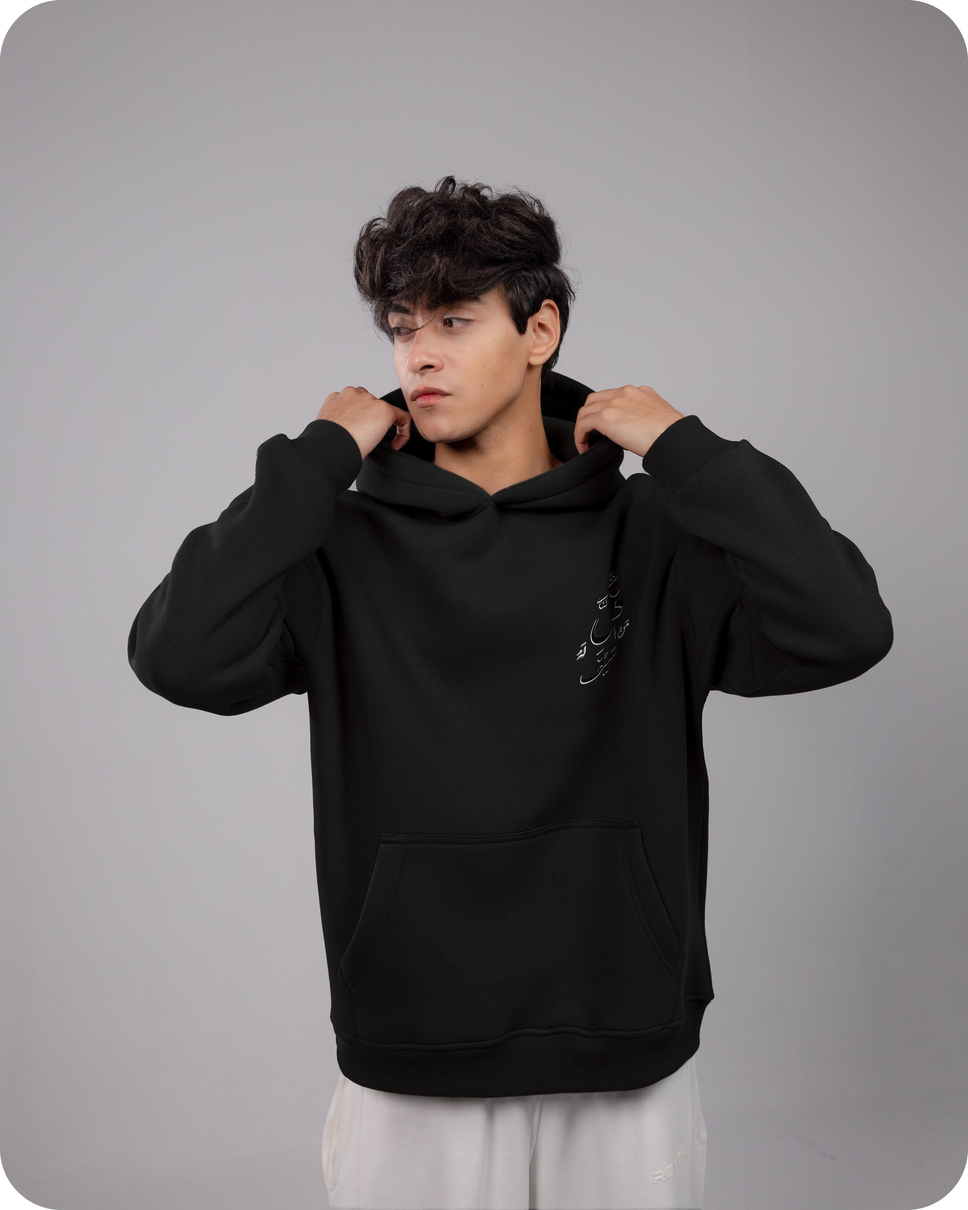 Person wearing a black hoodie against a gray background
