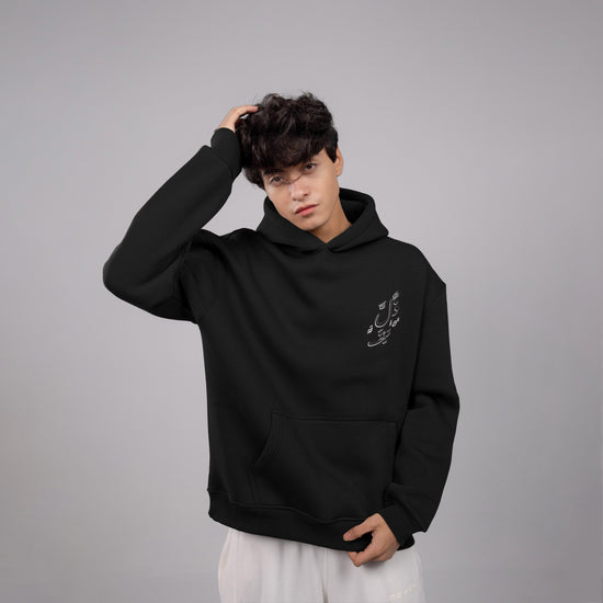 Person wearing a black hoodie with a small design on a gray background