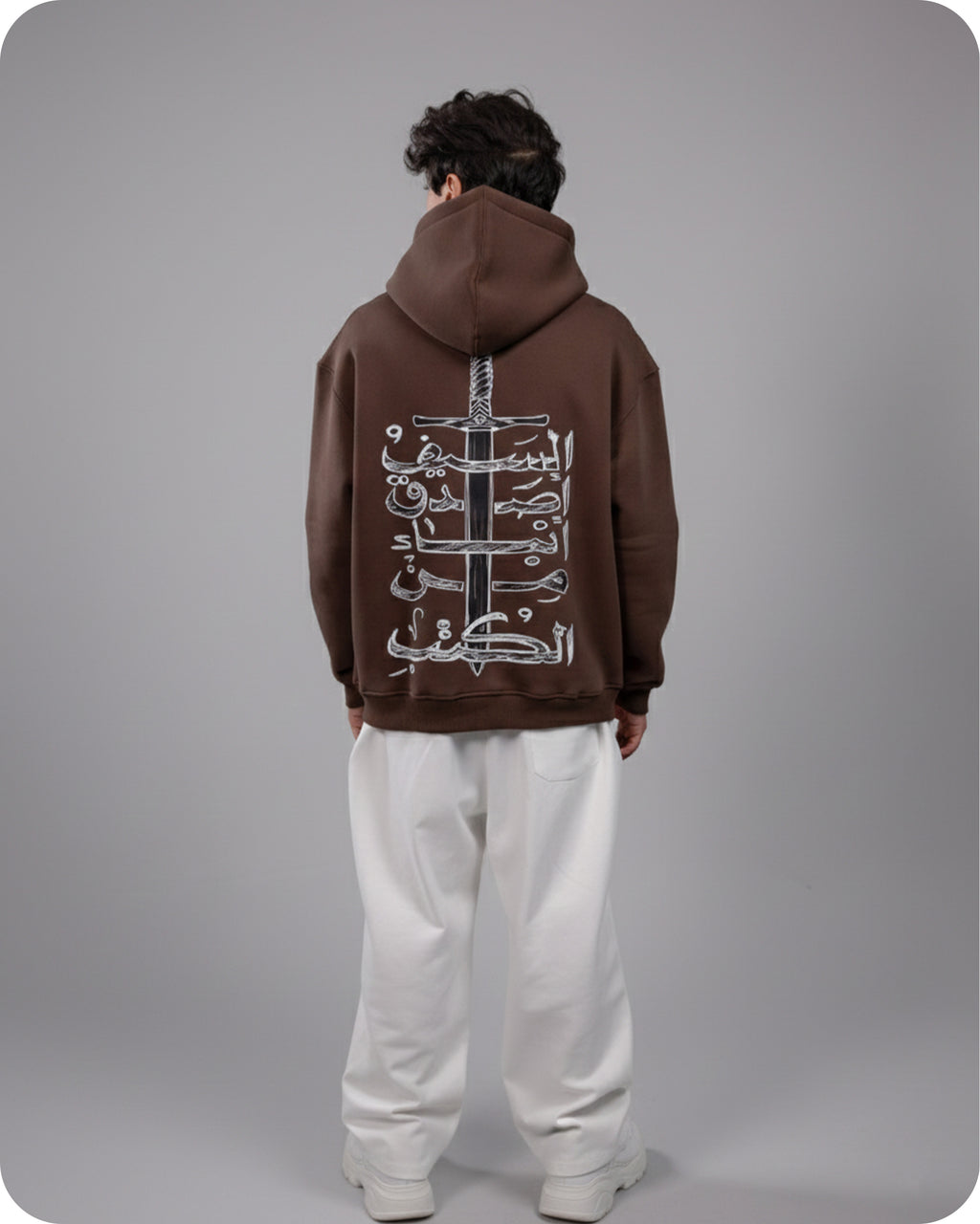Person wearing a brown hoodie with white designs on the back against a gray background