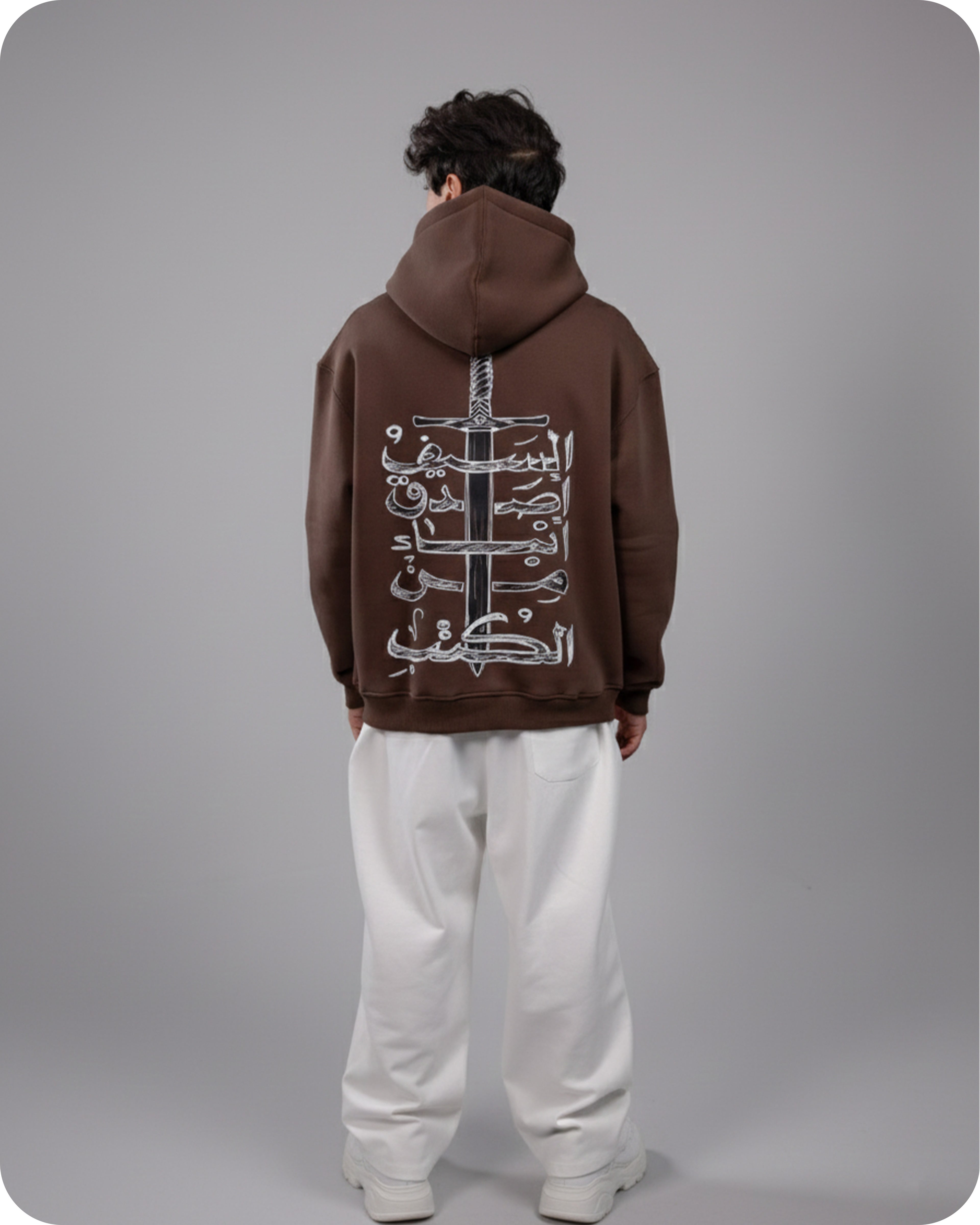 Person wearing a brown hoodie with white designs on the back against a gray background