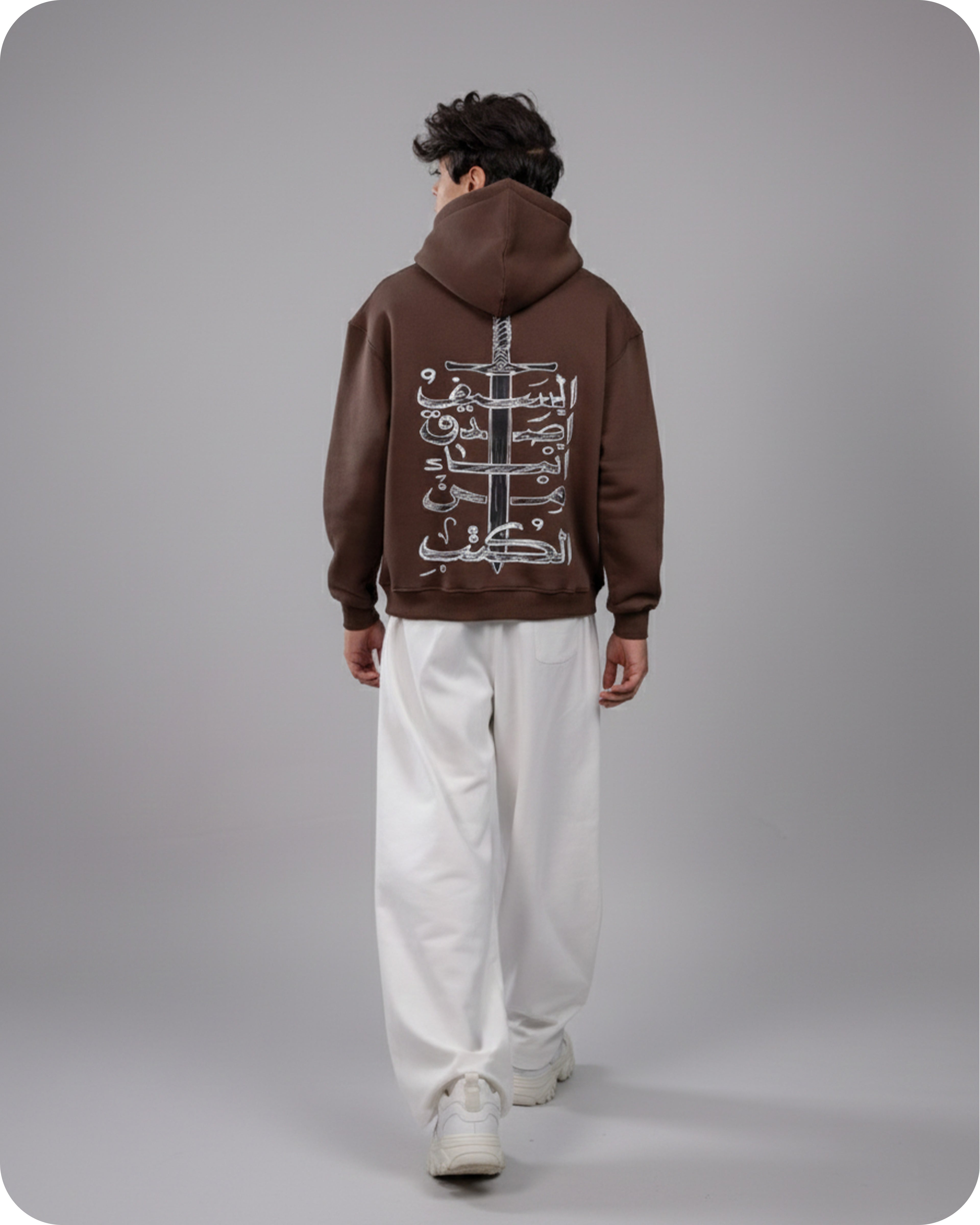 Person wearing a brown hoodie with a design on the back against a gray background