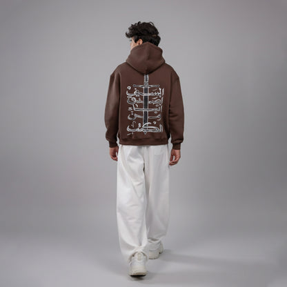 Person wearing a brown hoodie with a design on the back against a gray background
