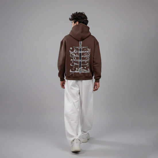 Person wearing a brown hoodie with a design on the back against a gray background