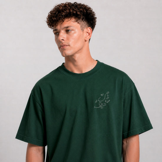 Man wearing a dark green t-shirt with a small graphic on a plain background