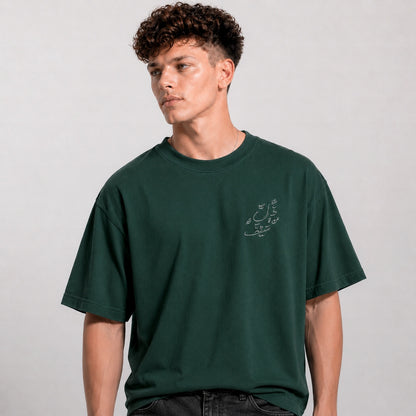 Man wearing a green t-shirt with a small graphic on a plain background