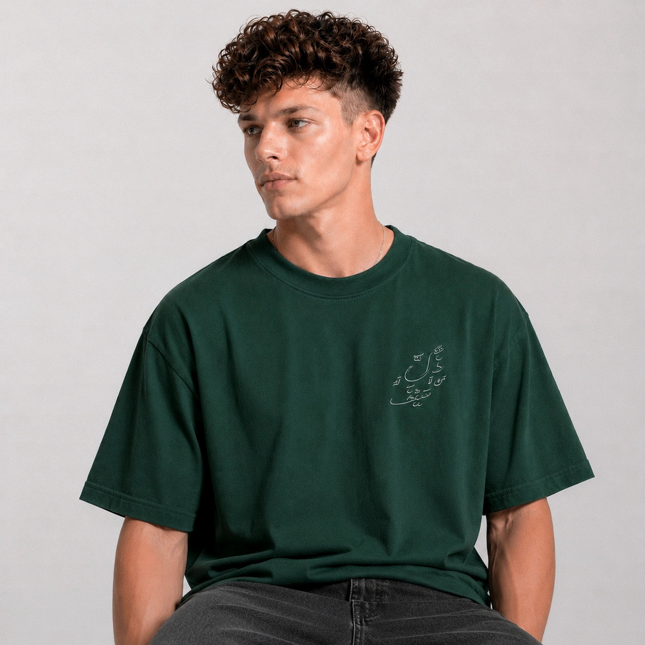 Man wearing a green t-shirt with a small design on a plain background