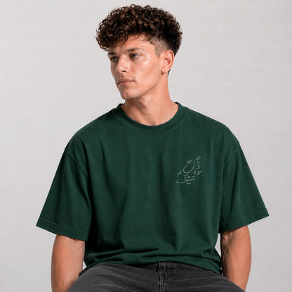 Man wearing a green t-shirt with a small design on a plain background
