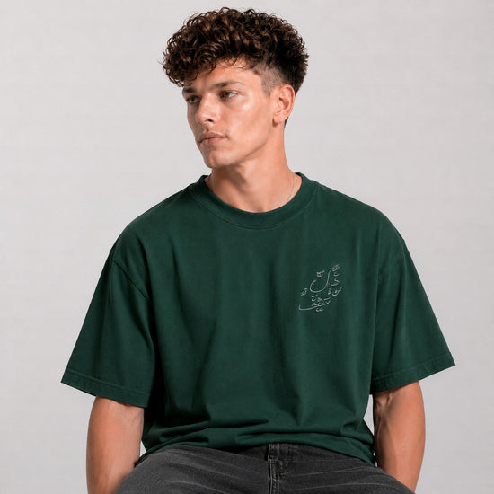 Man wearing a green t-shirt with a small design on a plain background