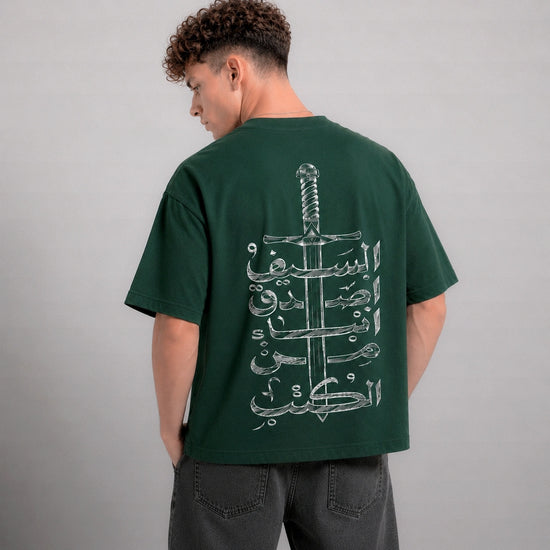 Person wearing a green t-shirt with a white graphic design on the back against a gray background