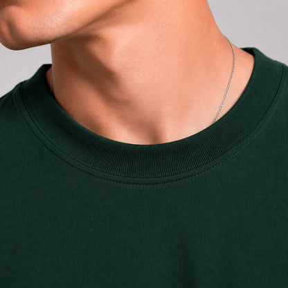 Close-up of a person wearing a dark green shirt with a plain background