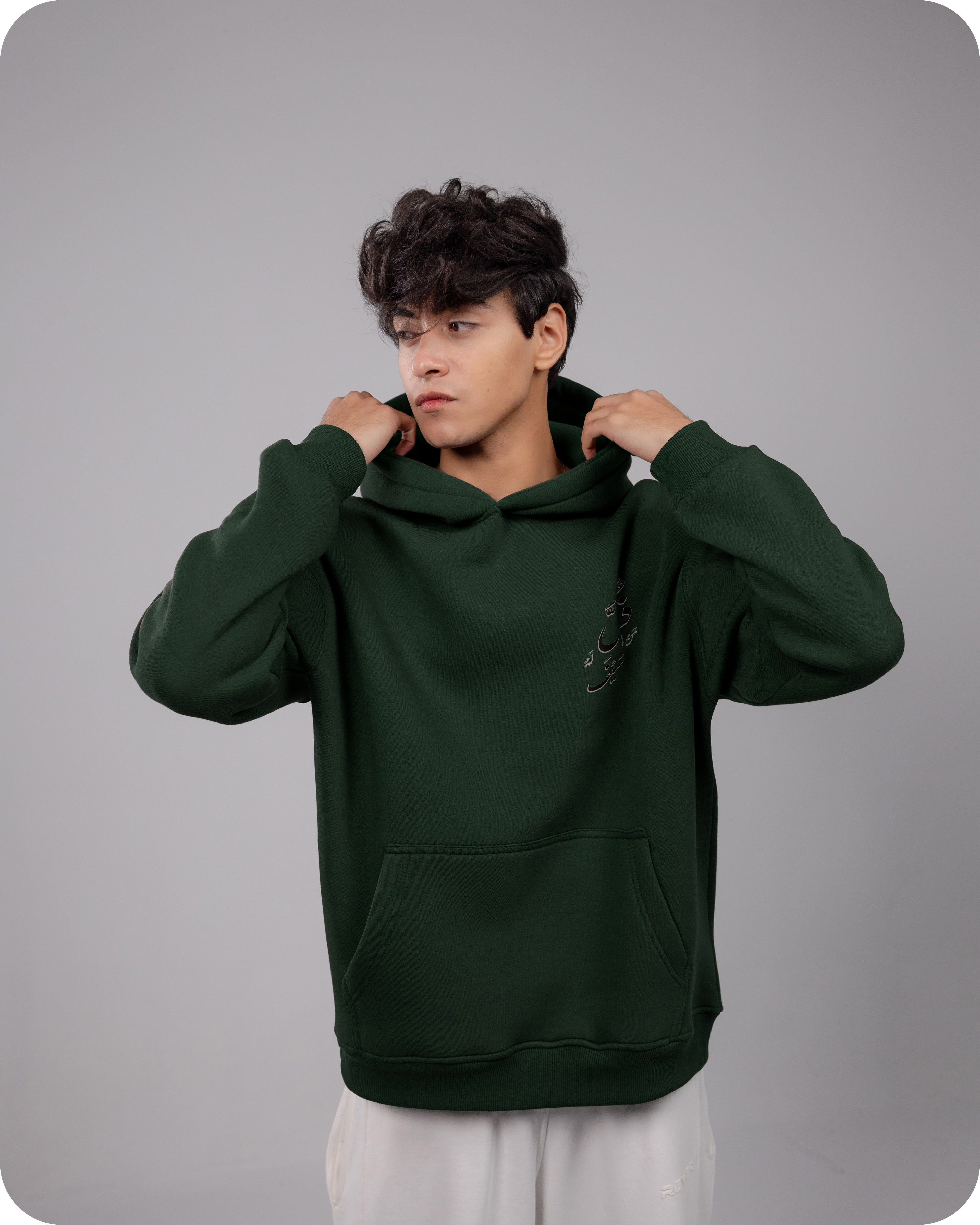 Person wearing a dark green hoodie against a gray background